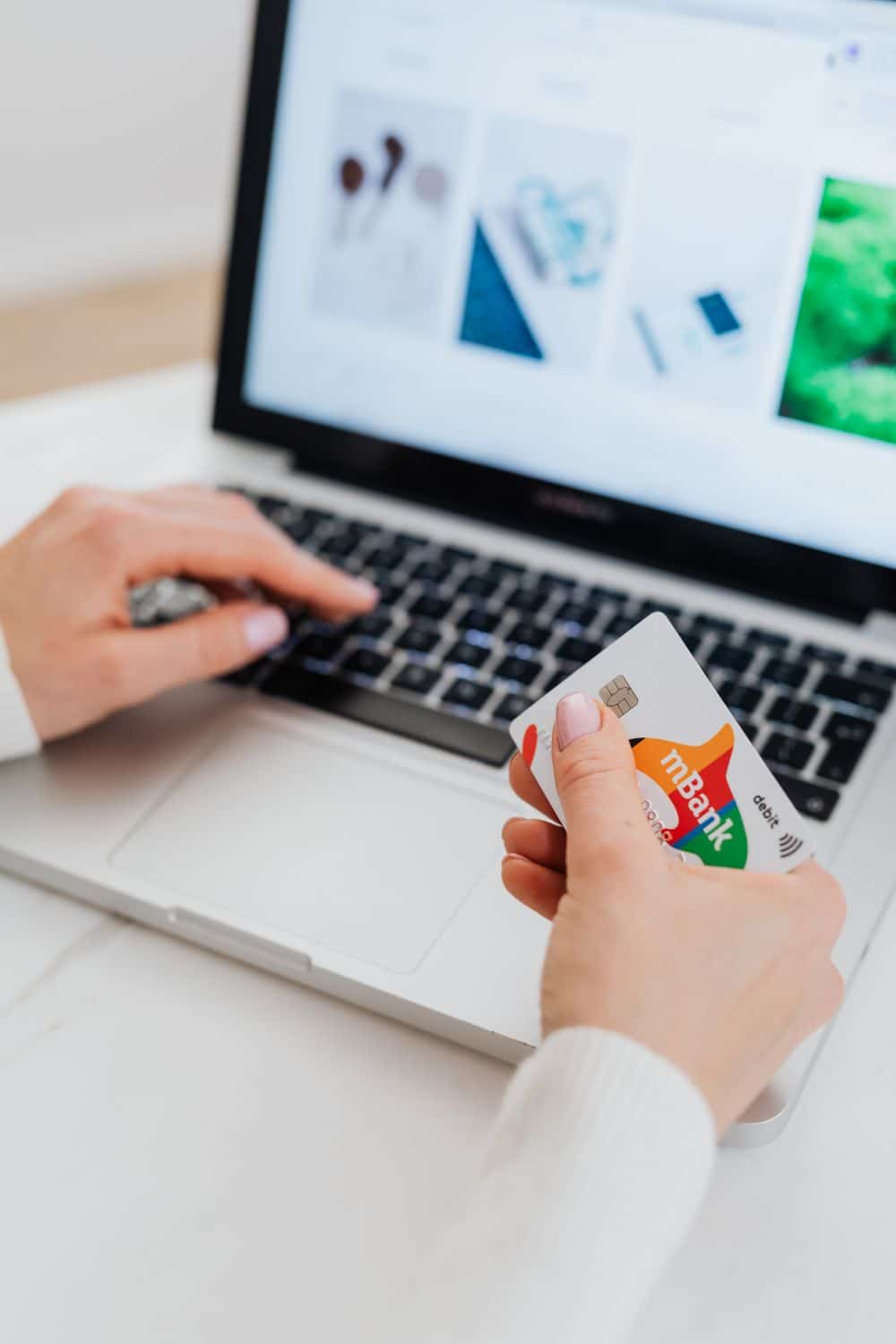 Person using a credit card for online shopping on a laptop, showcasing e-commerce concept.