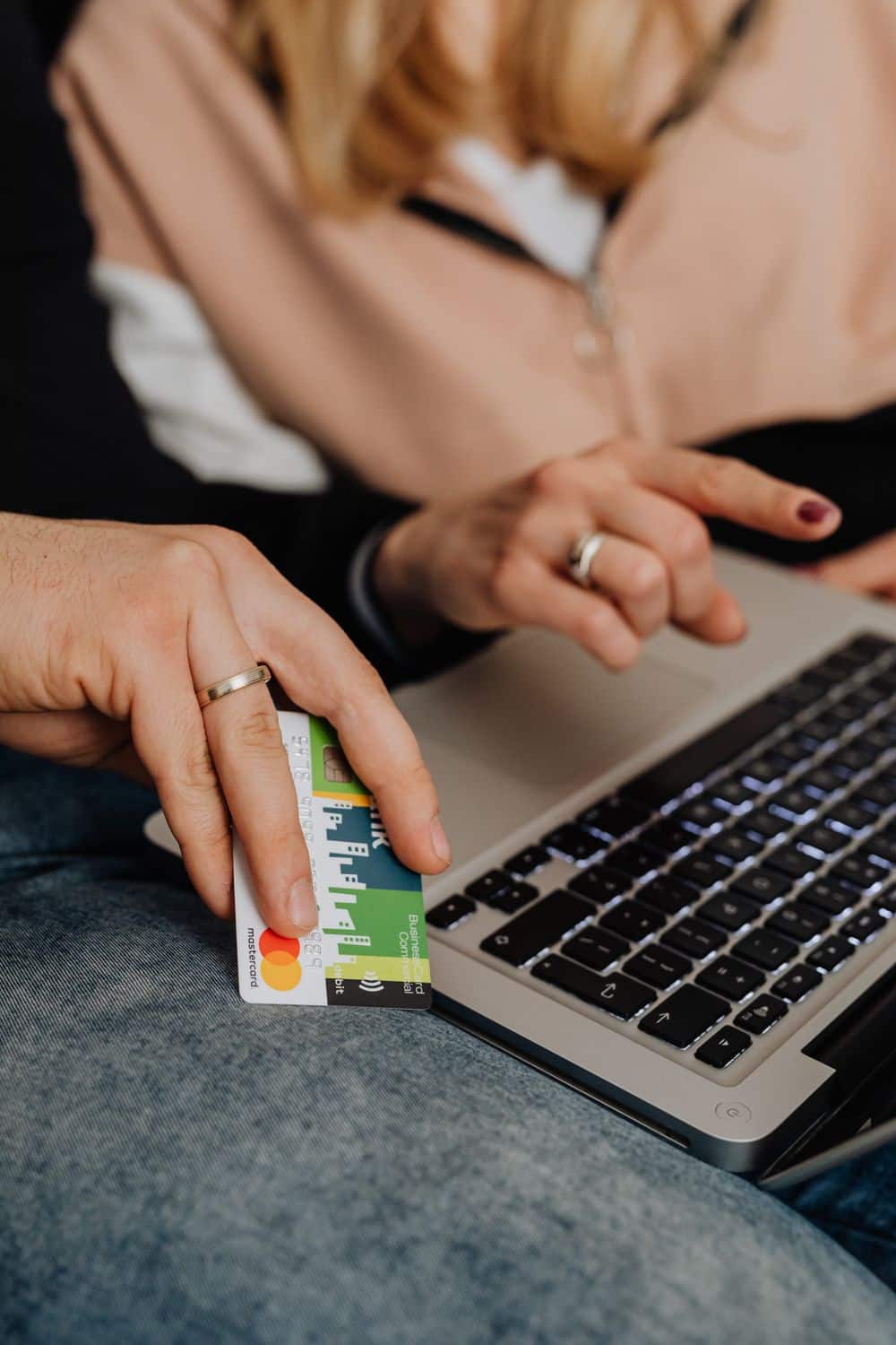 Close-up of a couple's hands using a laptop for online shopping with a credit card.
