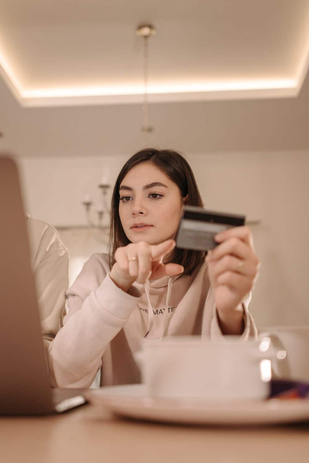 Woman holding credit card shopping online on laptop indoors.