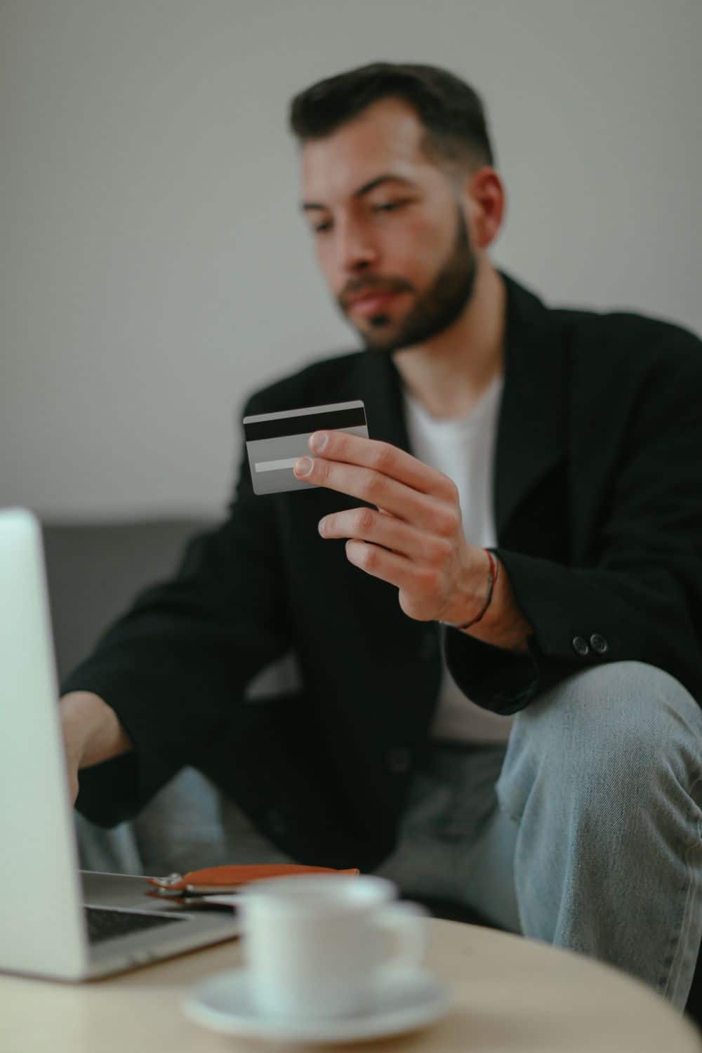 Focused man holding credit card while shopping online on his laptop at home.