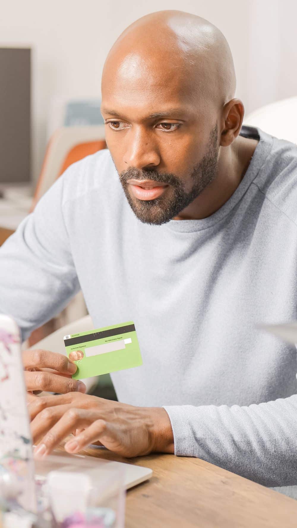Focused man using credit card for online shopping indoors, showcasing e-commerce convenience.