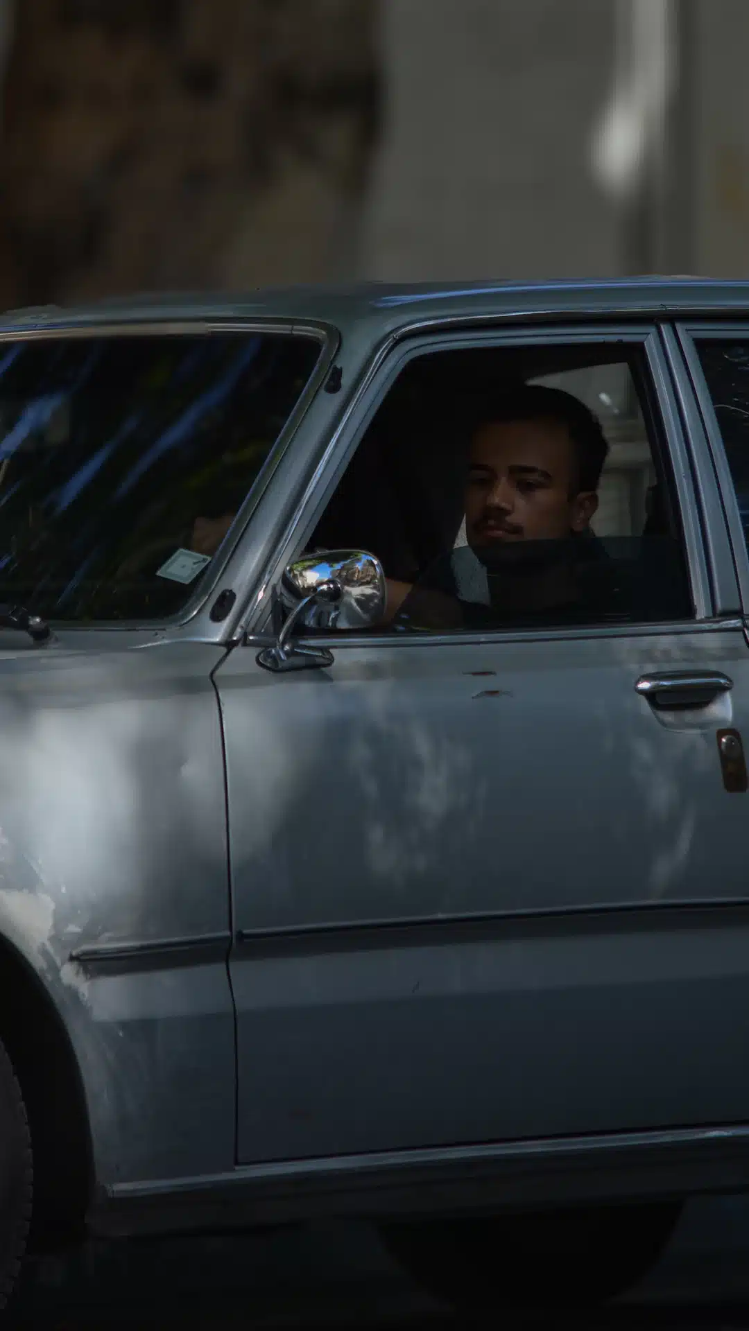 Man driving an old silver car