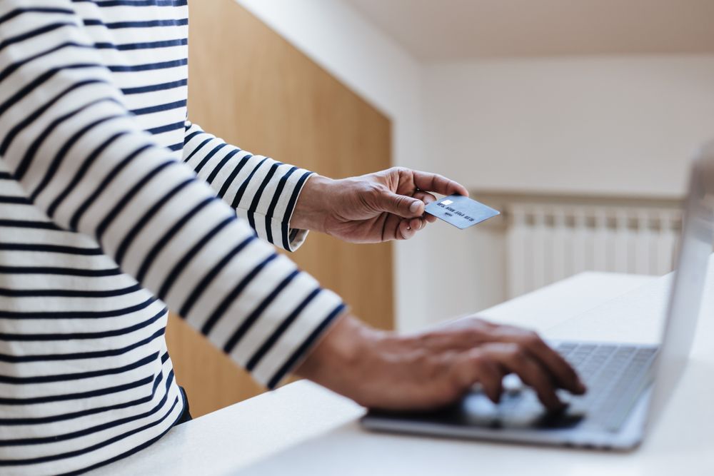 Person using a credit card for online shopping on a laptop indoors.
