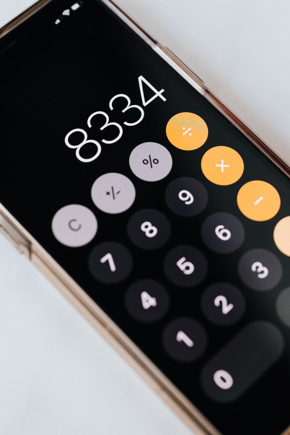 From above of modern cellphone in metal frame with open calculator application representing circles with numbers and symbols on black screen