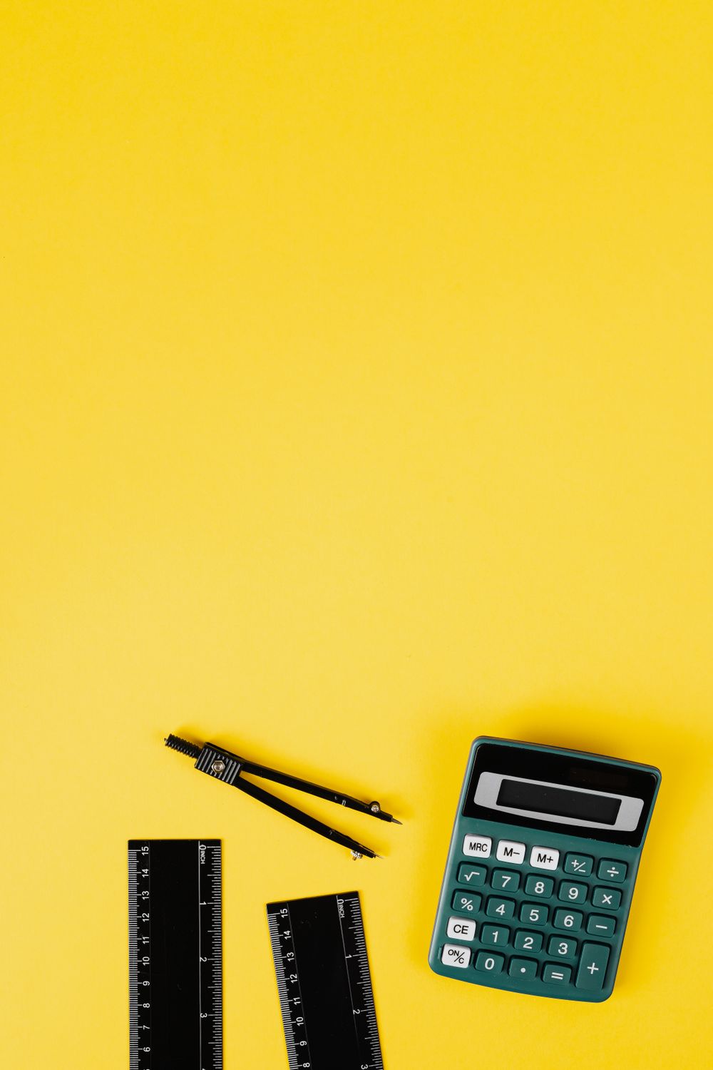 School supplies including a calculator and rulers on a yellow background for educational use.