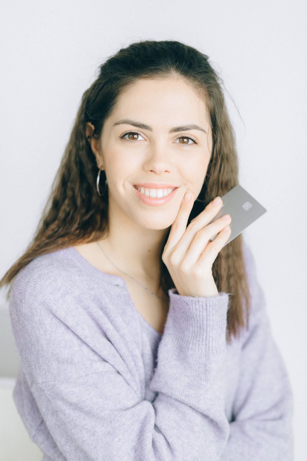 Financial independence concept with a smiling woman holding a credit card indoors.