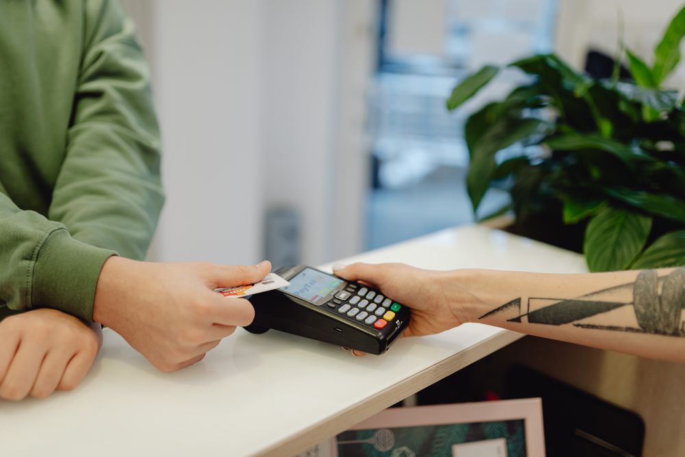 A close-up view of a contactless payment being made with a bank card over a payment terminal.