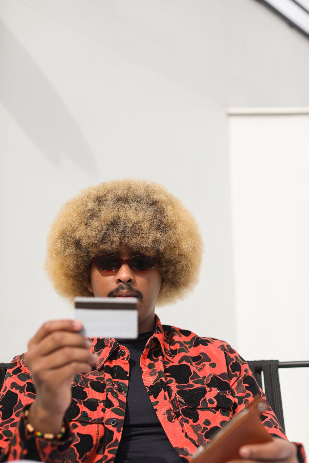 Stylish Afro American man in sunglasses making an online purchase using credit card outdoors.