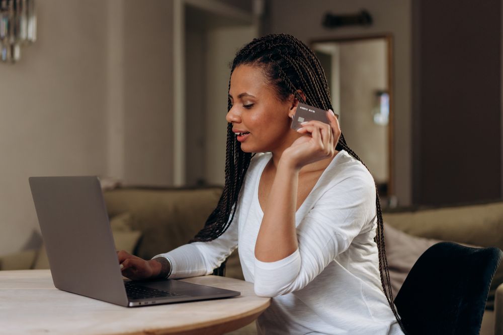 Woman shopping online at home using a laptop and credit card. Convenient cashless transaction concept.