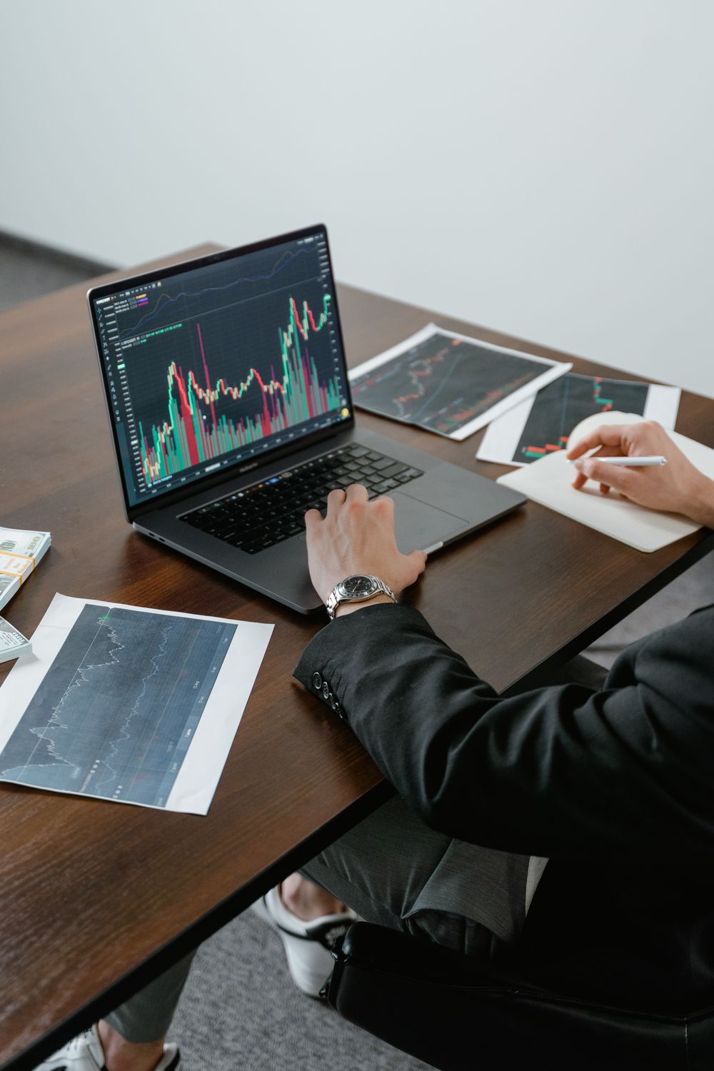 A business analyst reviewing stock charts on a laptop, analyzing market trends.