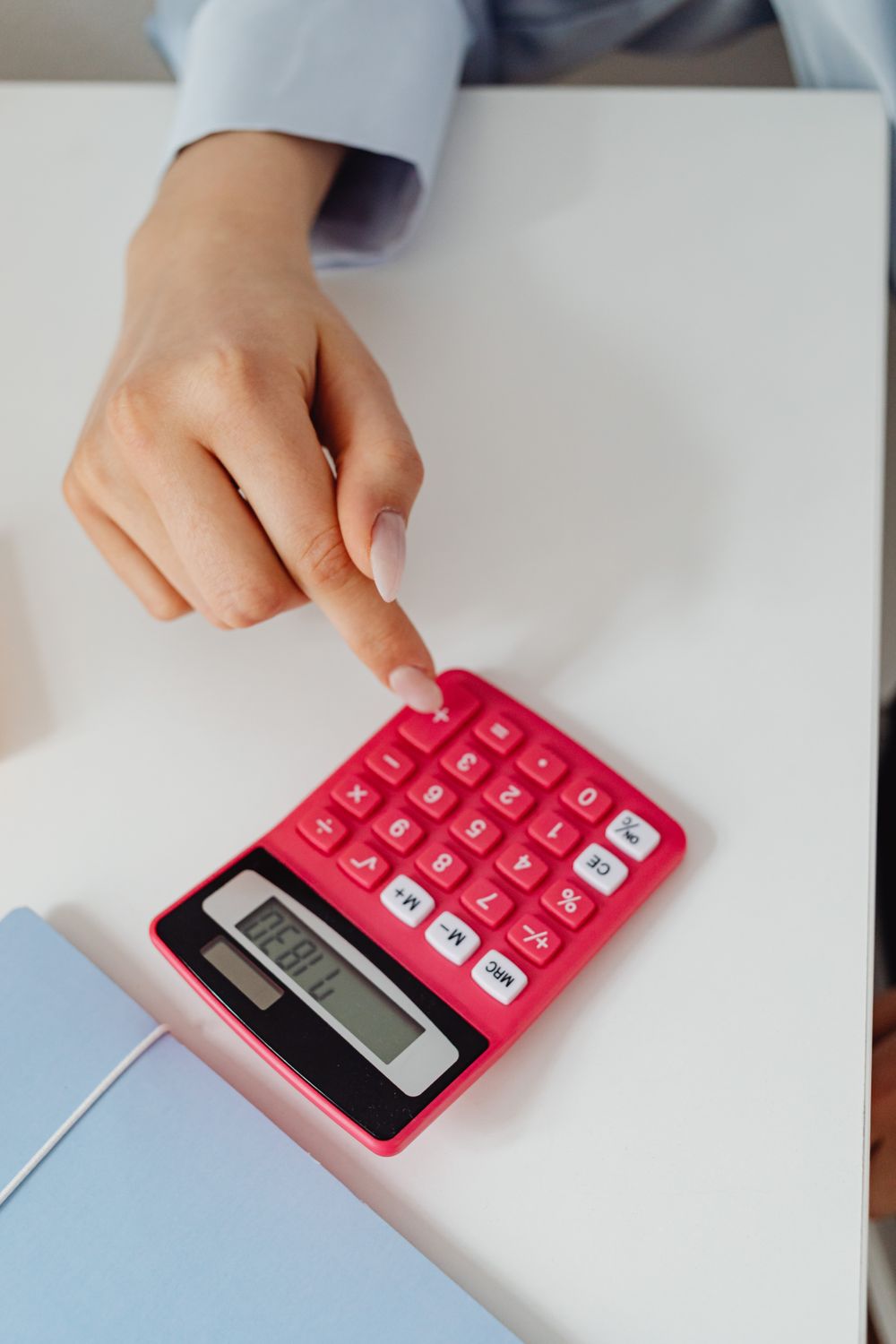 A person using a pink calculator on a white desk. This close-up captures precision in accounting work.