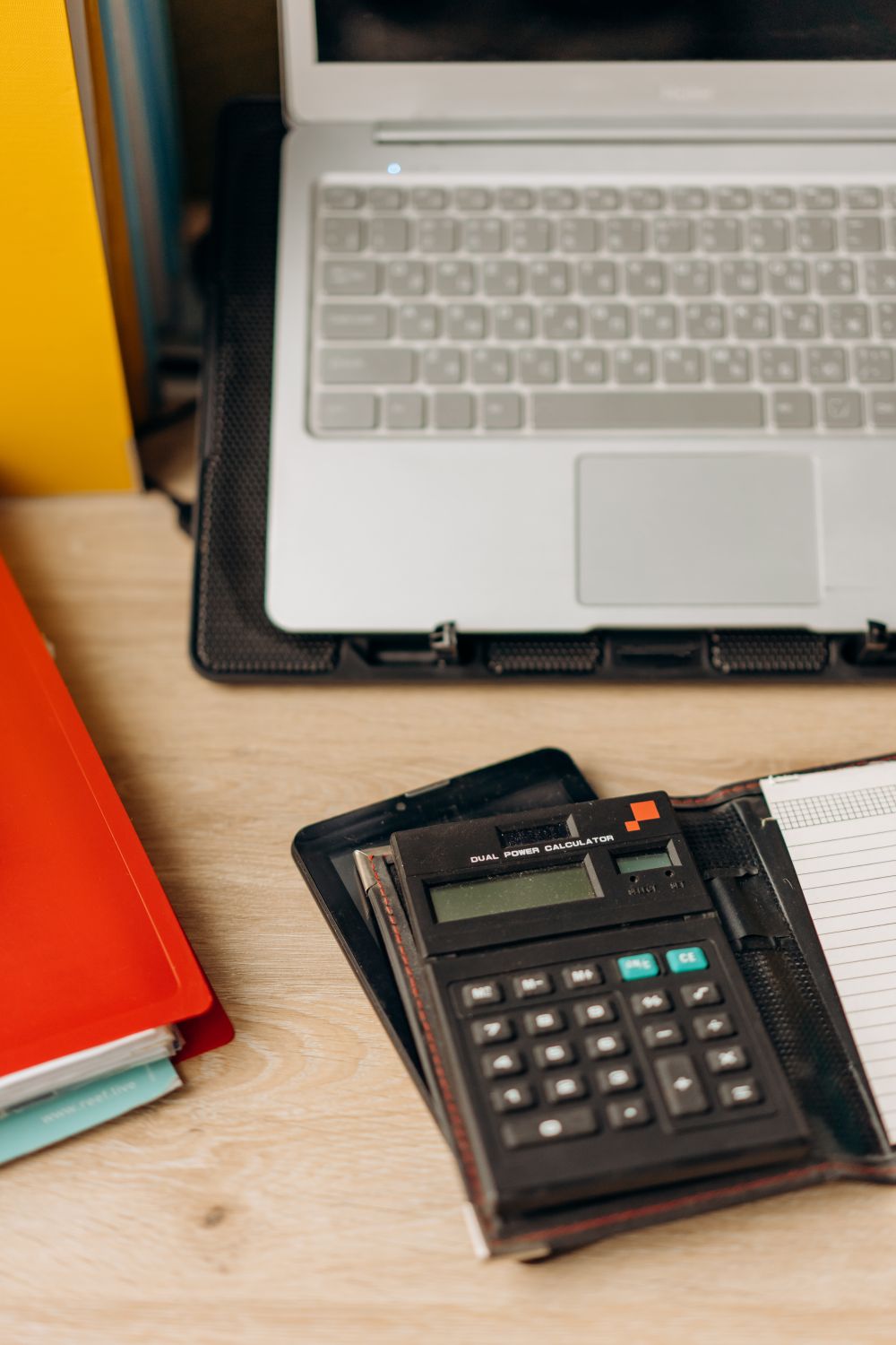 A well-organized workspace featuring a laptop and calculator on a wooden desk.