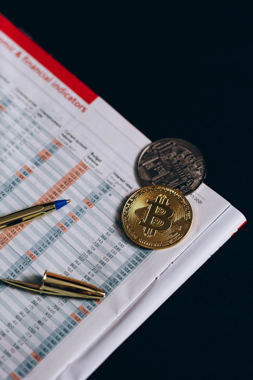 Close-up of Bitcoin and financial data with pen, symbolizing cryptocurrency investment.