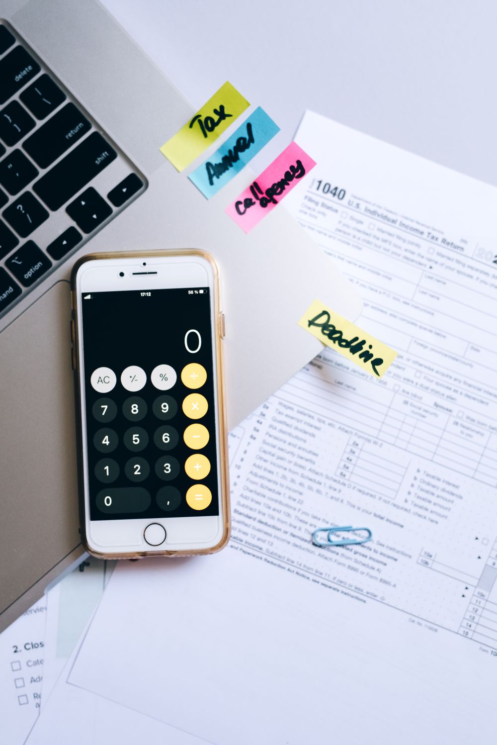 A smartphone calculator and tax forms on a desk, symbolizing financial planning.