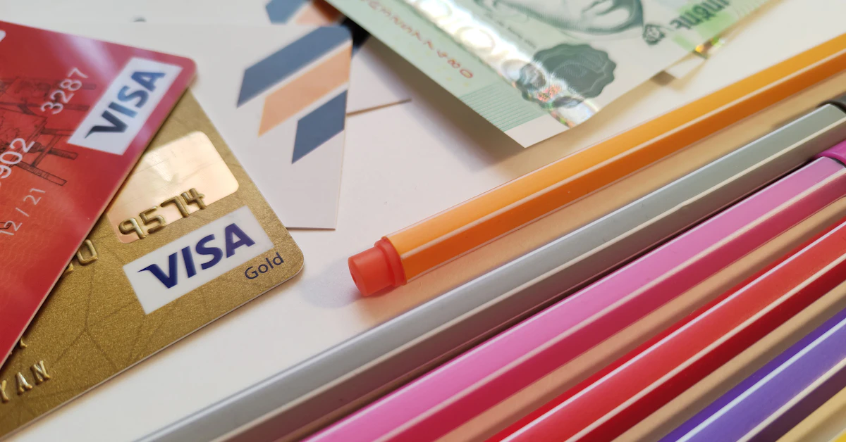 a pile of different colored pencils next to a credit card