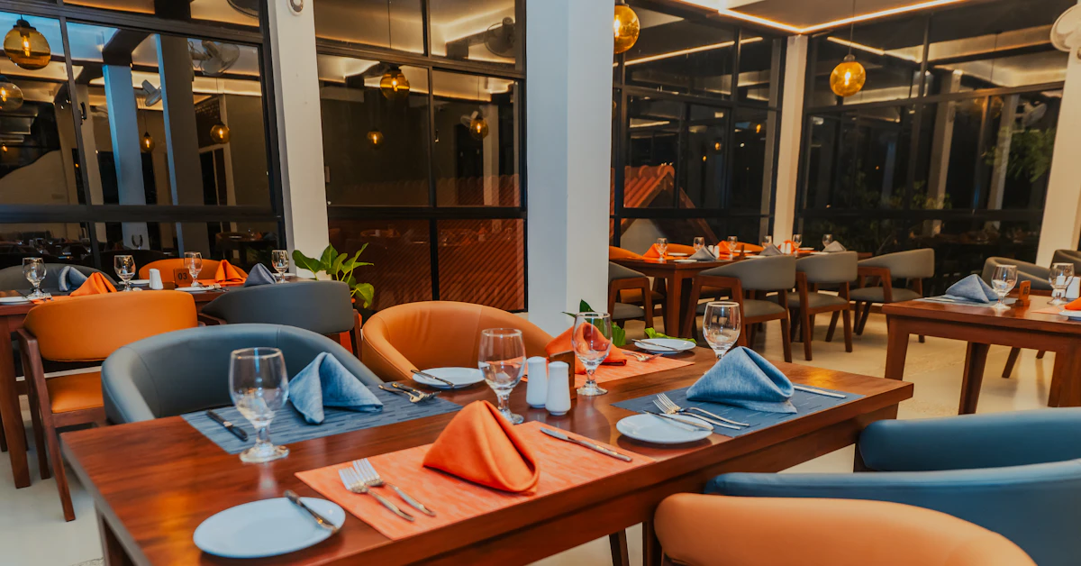 Tables set with orange napkins and blue placemats in a modern restaurant interior